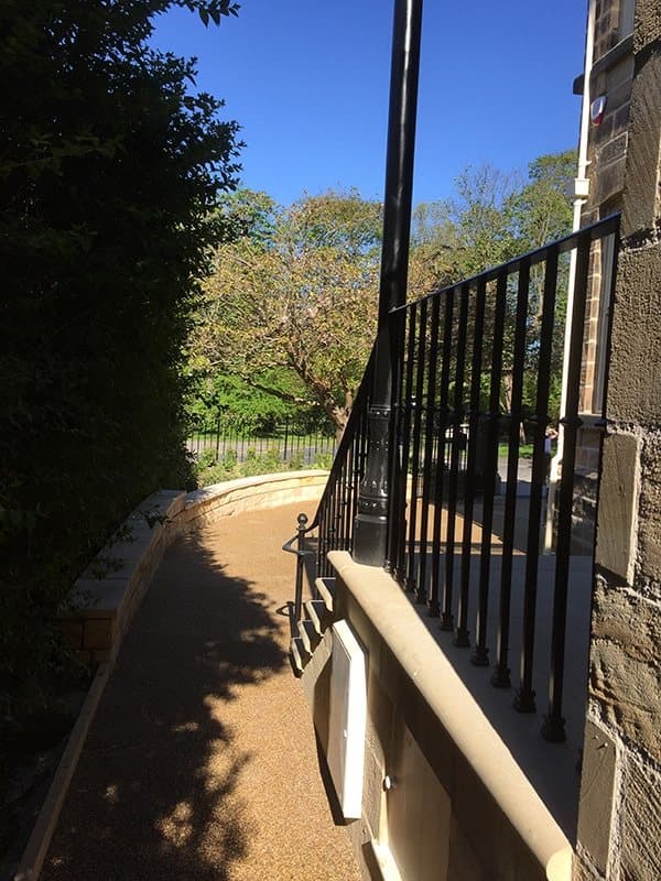 Black metal railings on a stone wall beside a curved side path